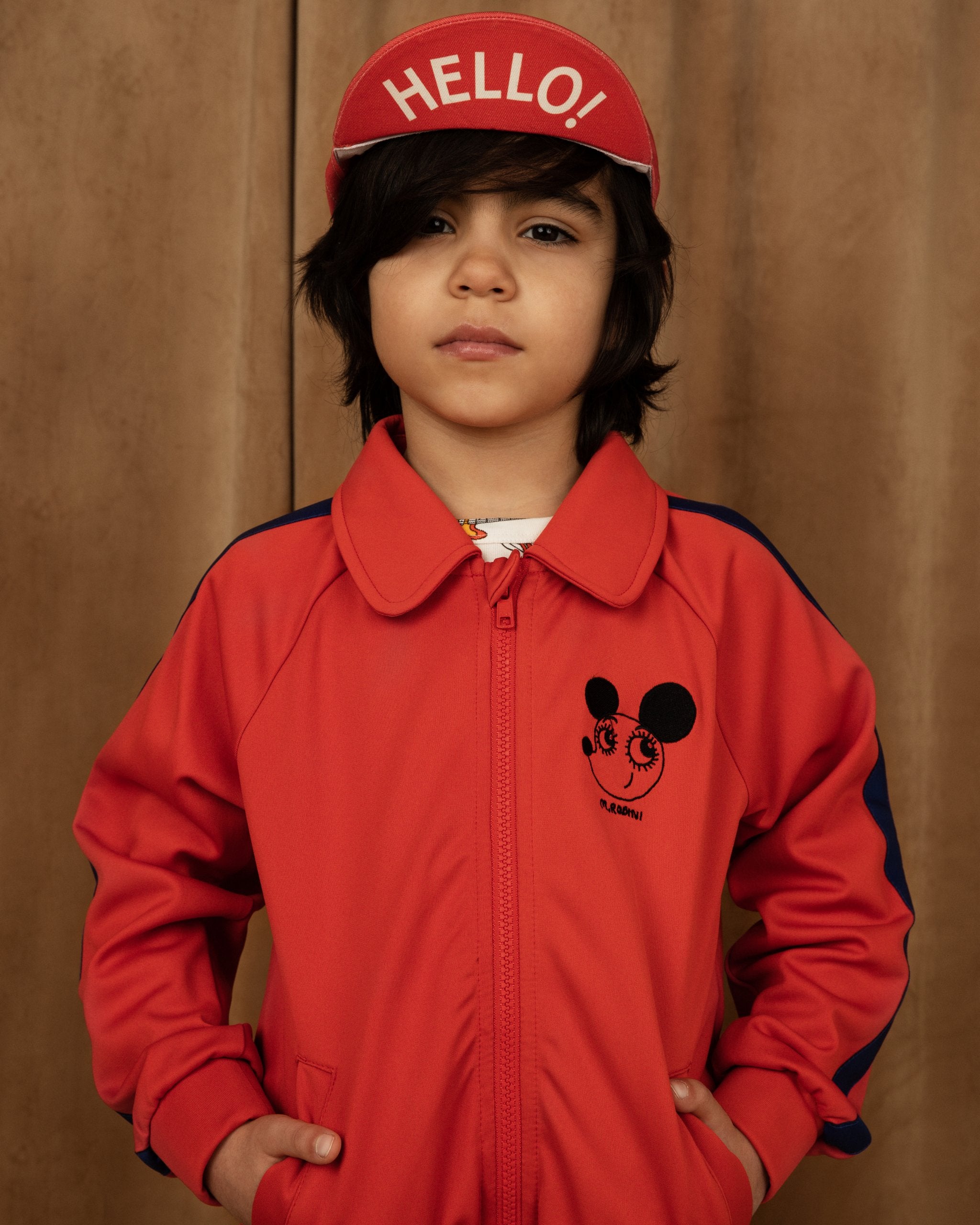 Collared track jacket with stripe detailing in red with mouse logo with child wearing a hat with hello word 